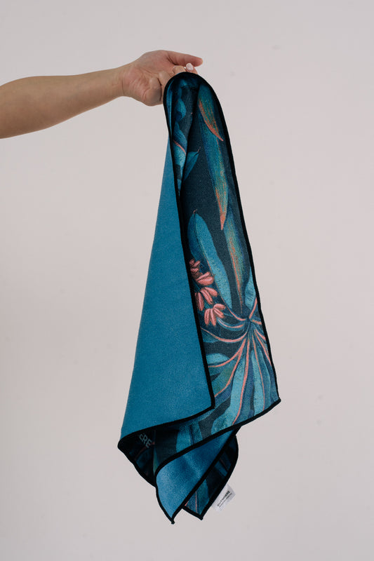 Hand holding Outwhere PH Everywhere towel by the logo tag, in Saging (banana) blue print showing the reverse color of the towel in blue