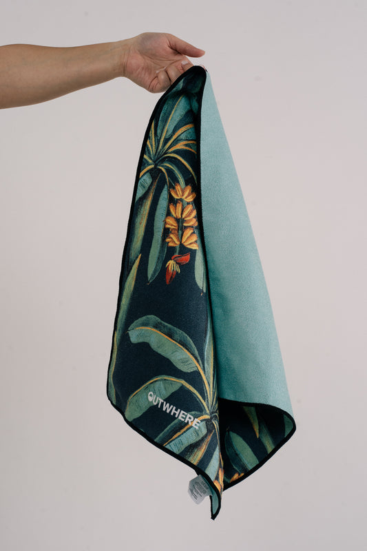 Hand holding Outwhere PH Everywhere towel by the logo tag, in Saging (banana) green print showing the reverse color of the towel in green