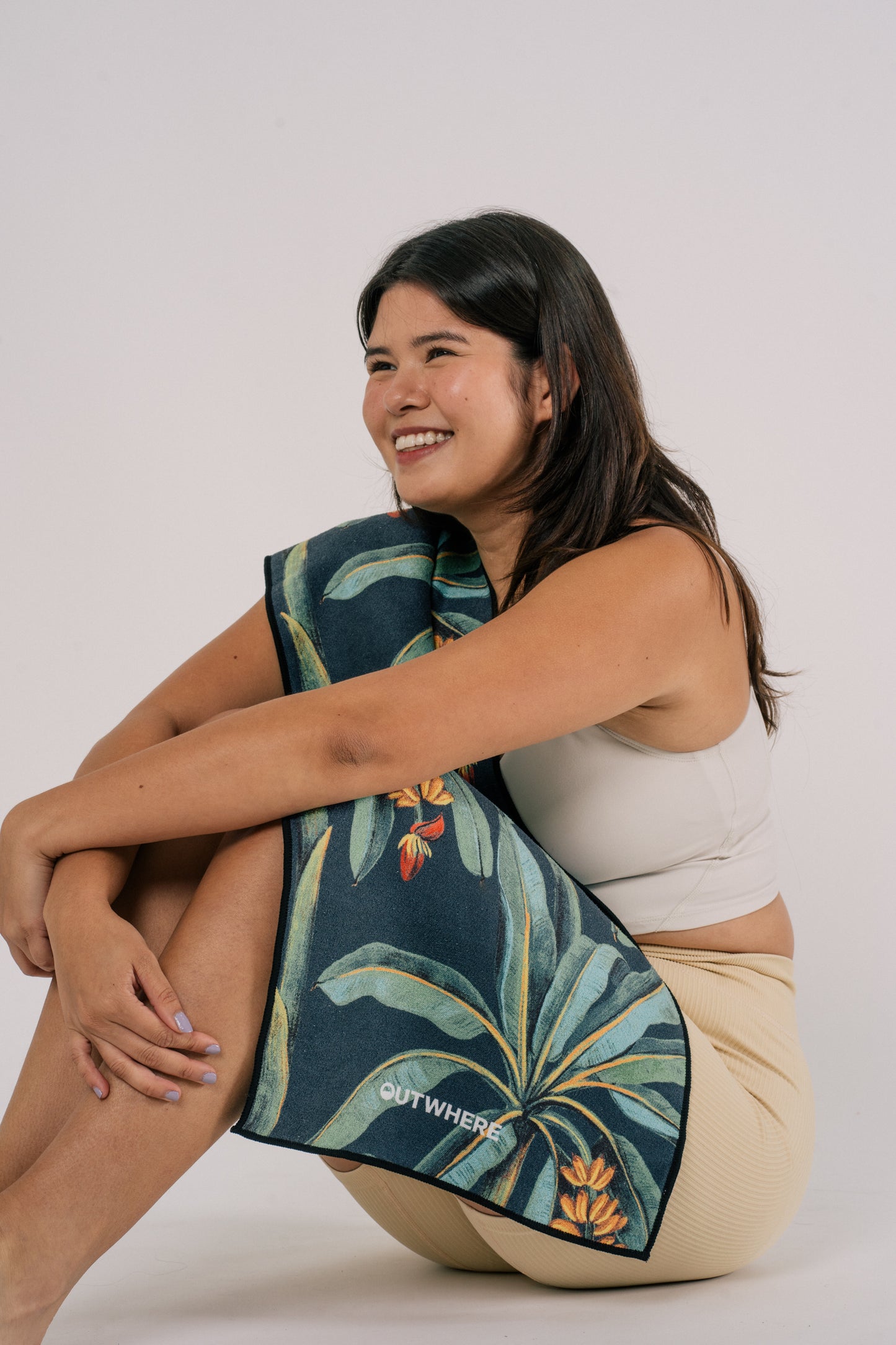 Female model sitting with Outwhere Ph Everywhere towel in Saging Green wrapped across her body