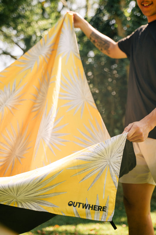 Man holding out the Outwhere PH Latag in Anahaw on both ends about to lay it on the grass in the park