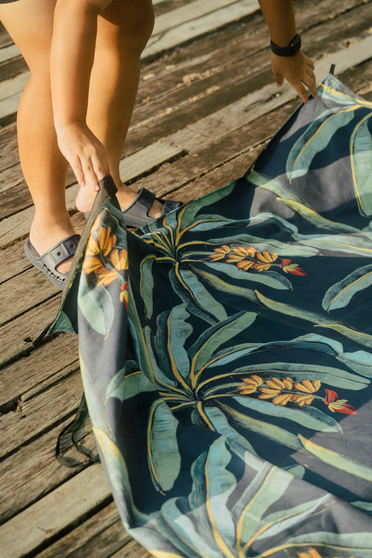 Hands laying out the Outwhere PH Latag mat in Saging on a wooden plank surface