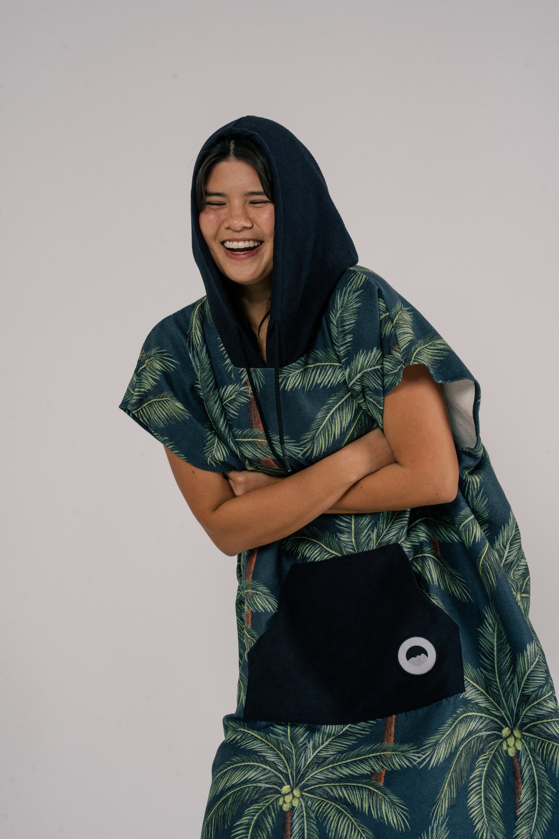 Female model smiling wearing Outwhere Changing Poncho Towel in Buko design, Coconut tree print