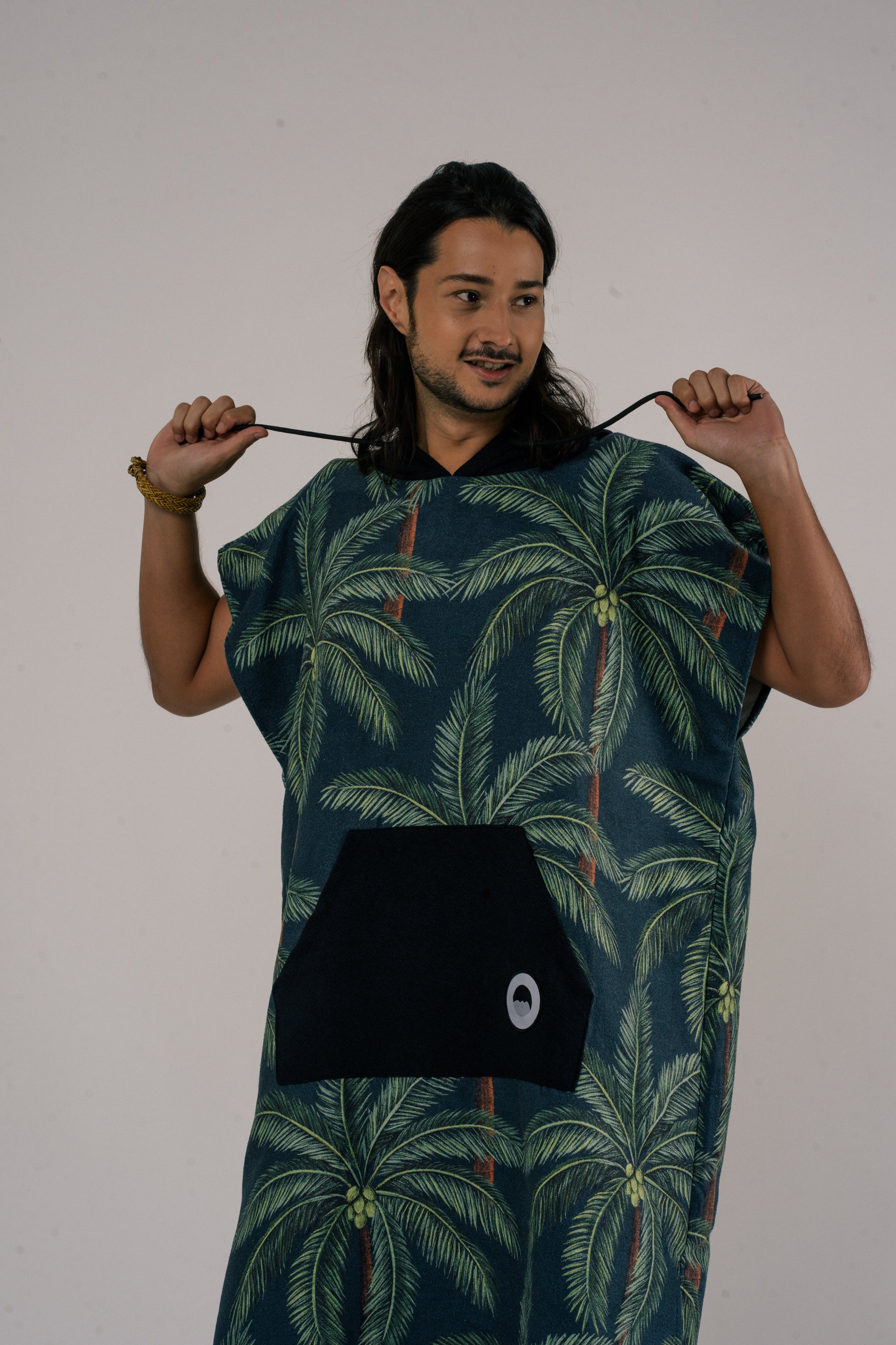 model wearing Outwhere Changing Poncho Towel in Buko design, Coconut tree print, holding drawstring hood