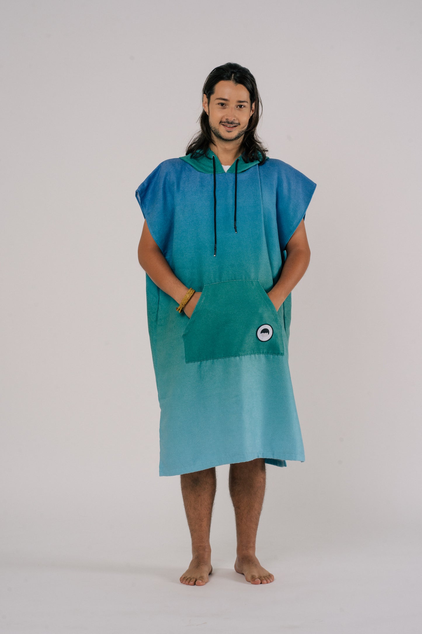 Male wearing Outwhere Changing Poncho Towel in Dagat (ocean) design, shades of blue and green