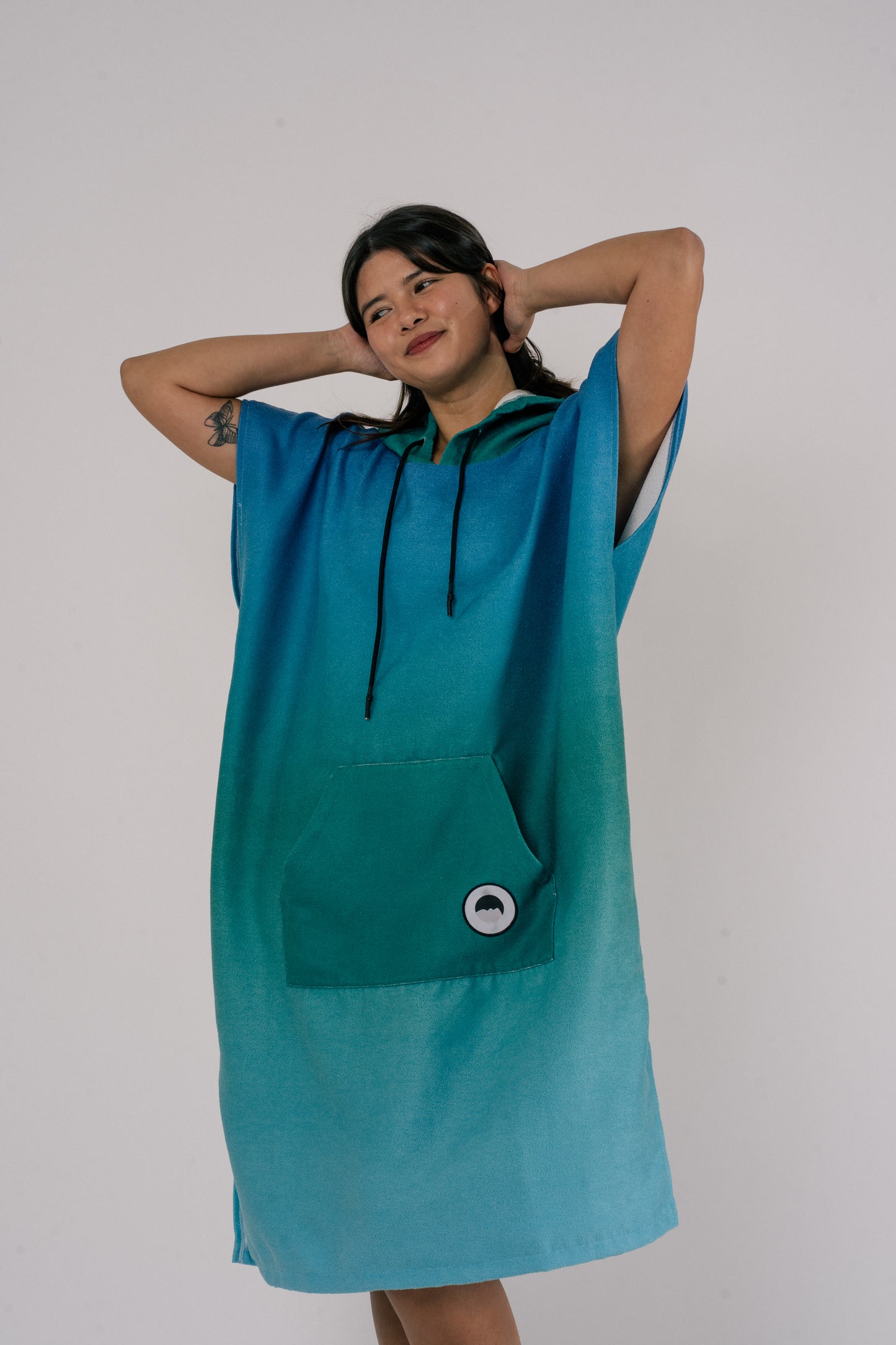 Female wearing Outwhere Changing Poncho Towel in Dagat (ocean) design, shades of blue and green