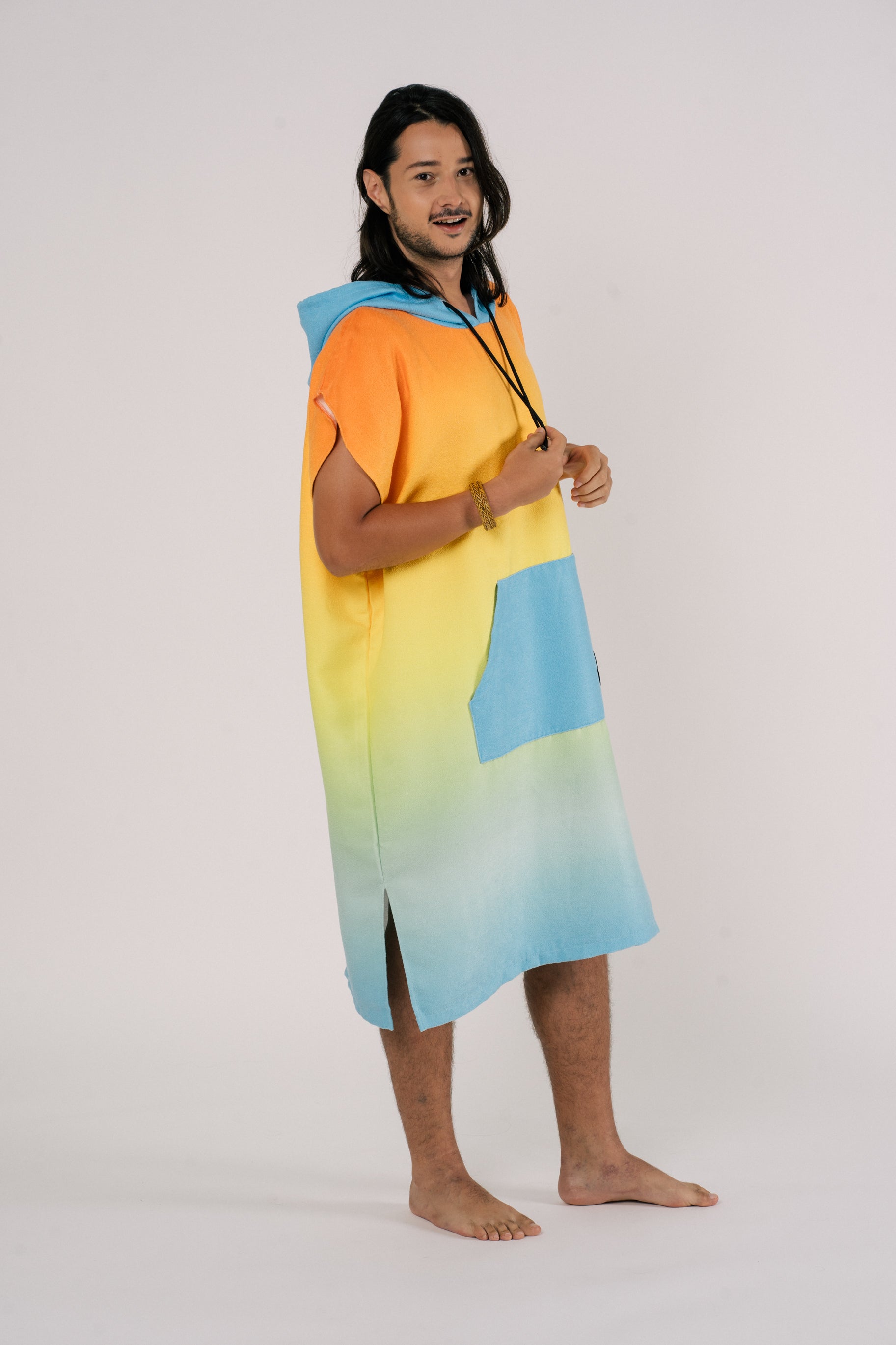 Male wearing Outwhere Changing Poncho Towel in Liwayway (dawn) design, gradient shades of orange, turquoise, yellow, green