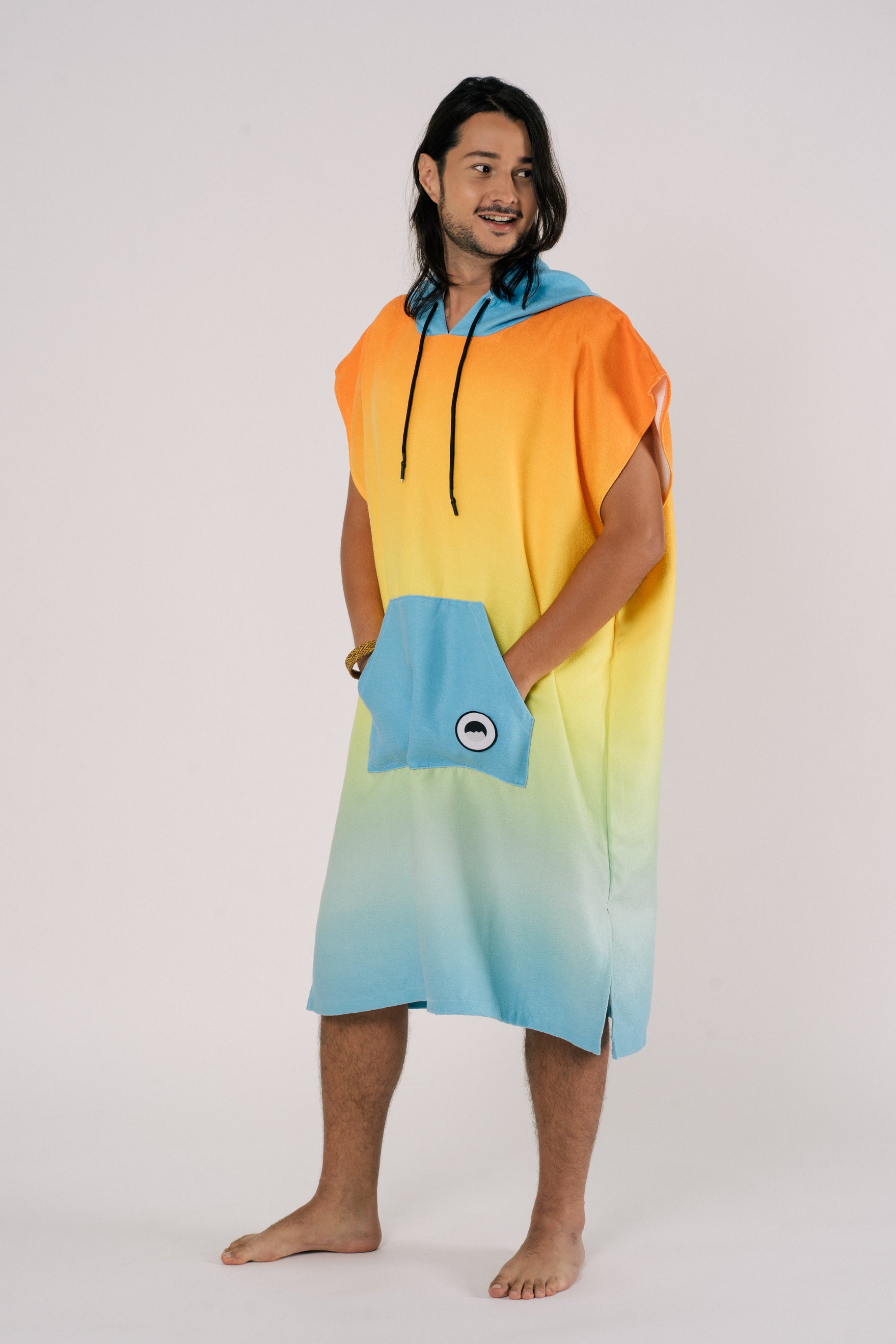 Male wearing Outwhere Changing Poncho Towel in Liwayway (dawn) design, gradient shades of orange, turquoise, yellow, green