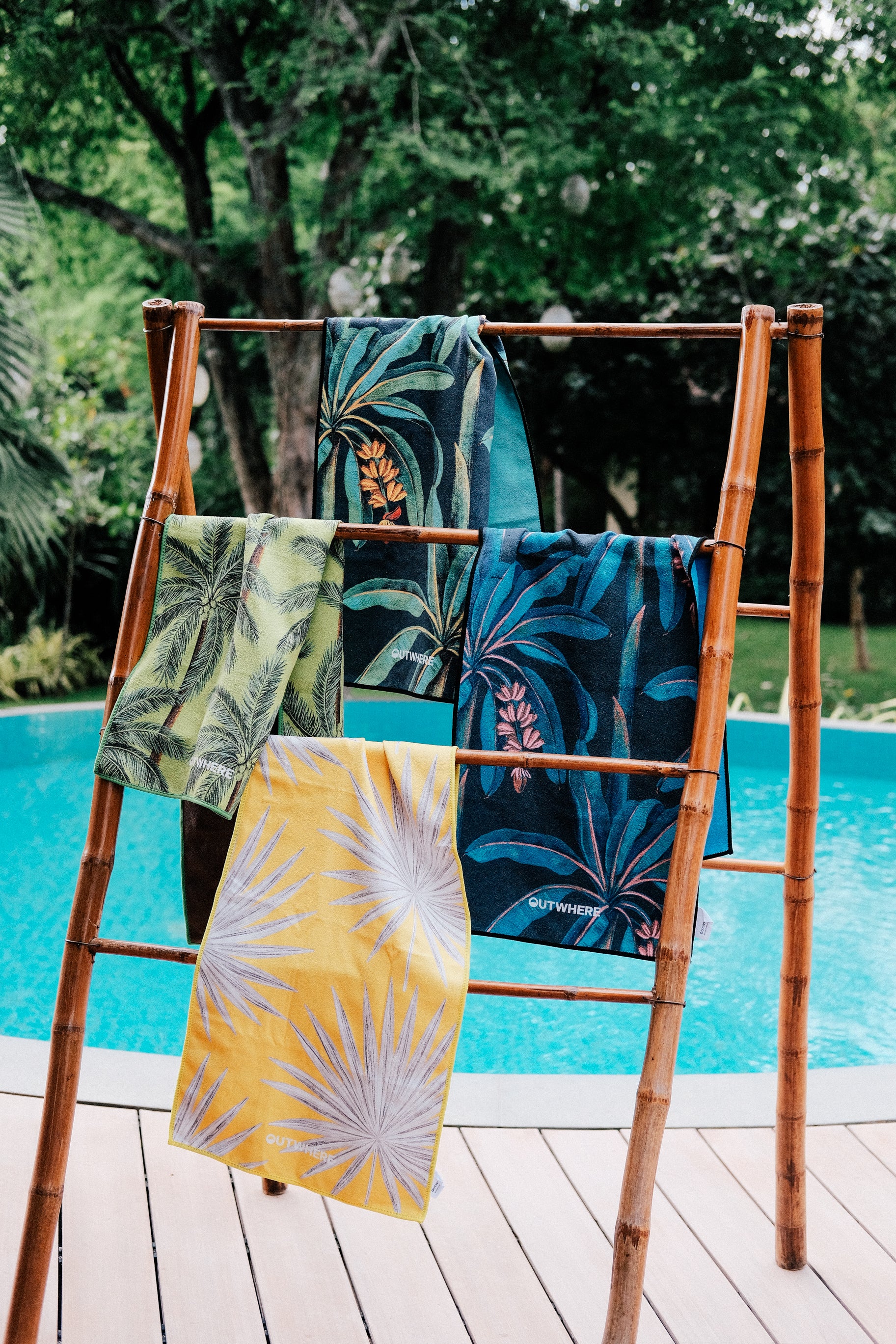 Outwhere PH Everywhere Towel 4-pack tropical themed towels hung on hanger with a pool background