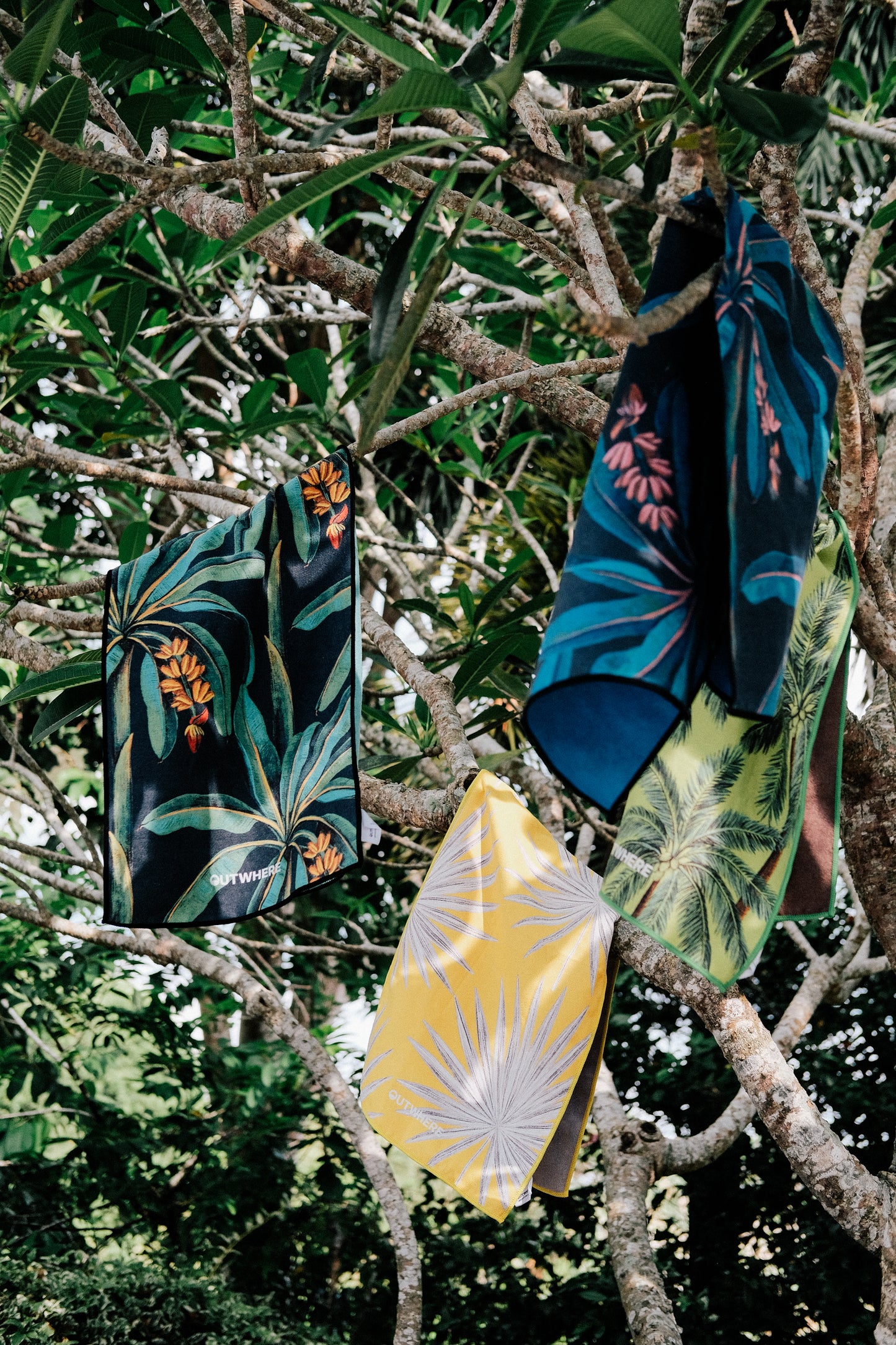 Outwhere PH Everywhere Towel 4-pack tropical themed towels hung on tree 