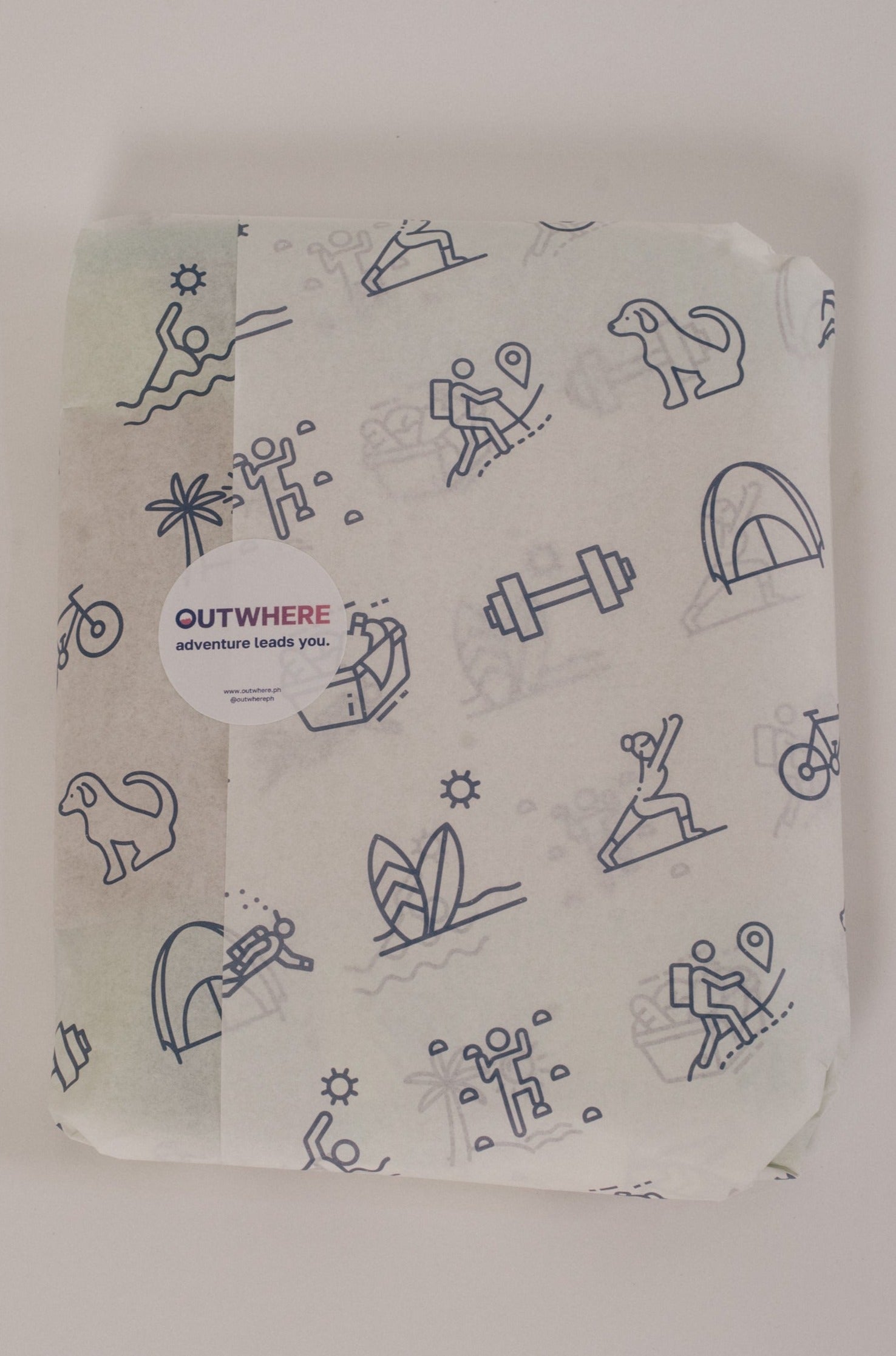 Outwhere PH Everywhere towel packaged in white paper with icons design, sealed with a sticker that says OUT WHERE ADVENTURE LEADS YOU.