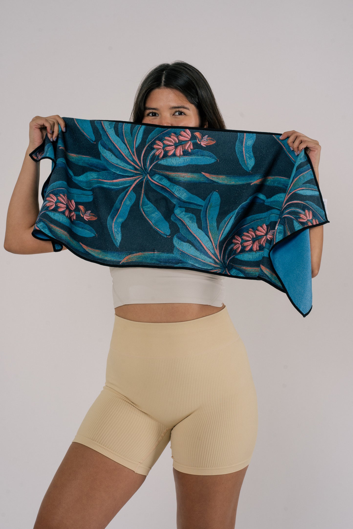 Female model holding Outwhere Ph Everywhere towel in Saging blue covering her face
