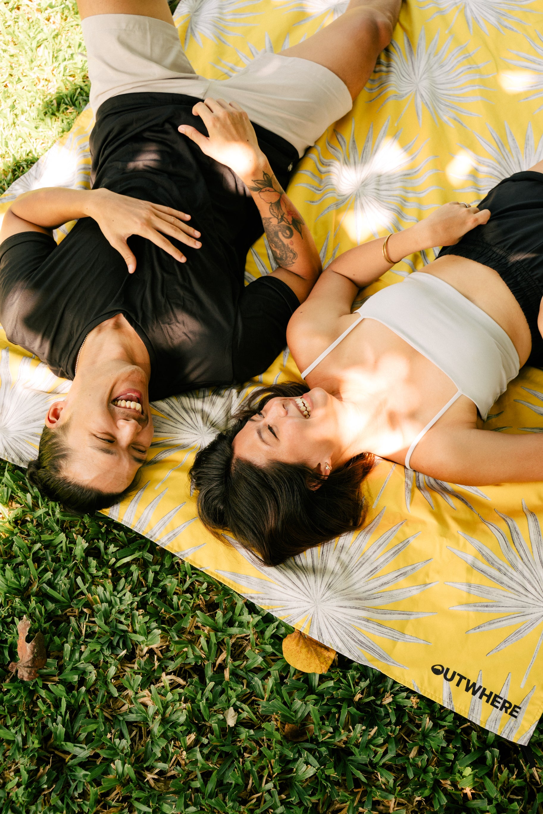 Couple lying down on the Outwhere PH Latag mat in Anahaw on the grass